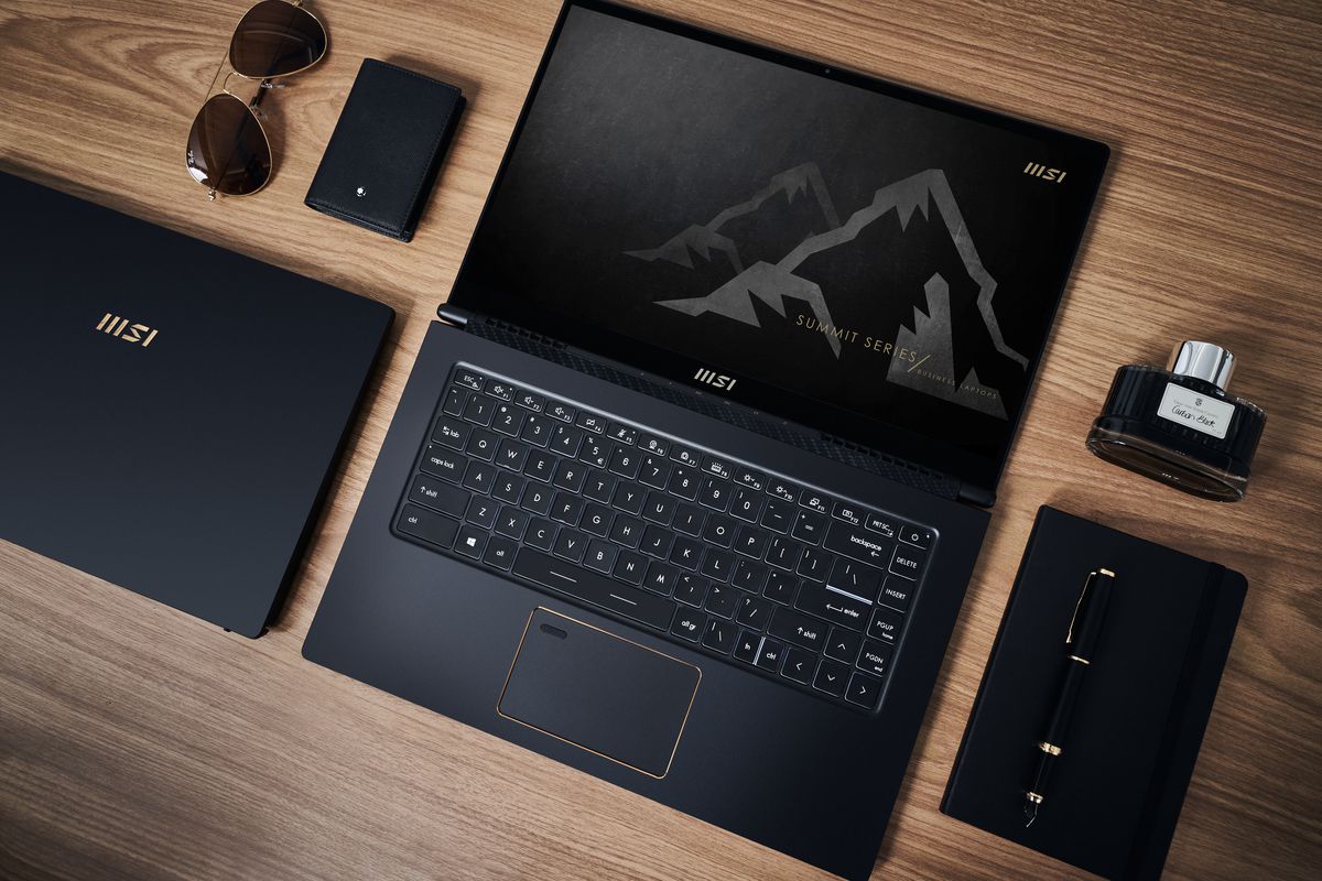 An MSI Summit Series laptop open flat on a desk, alongside other black accessories.