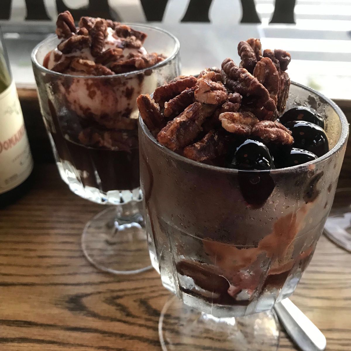 A pair of gelato sundaes topped with pecans