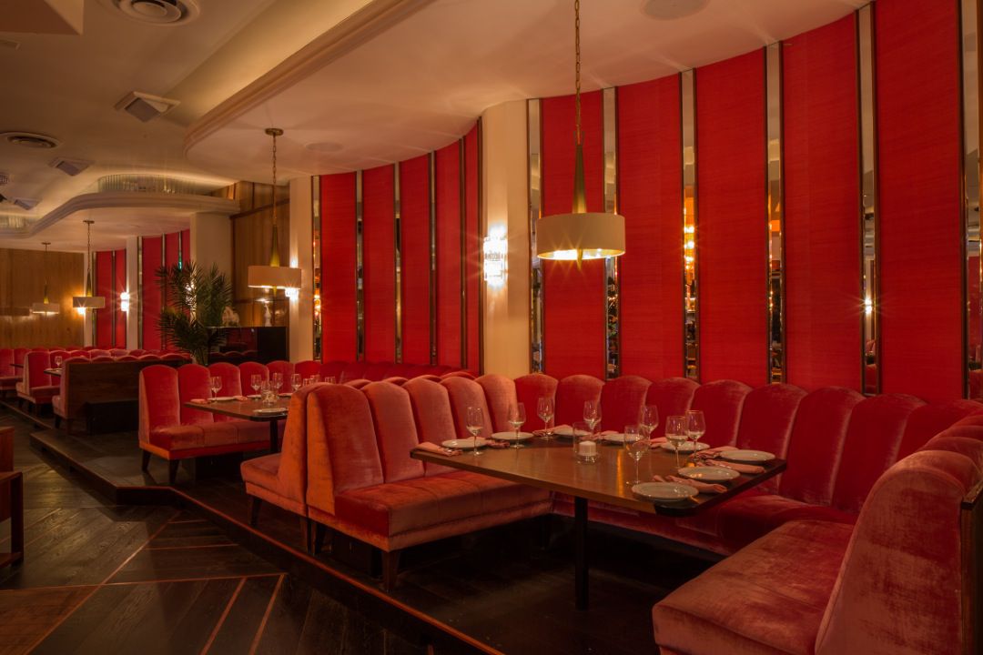 Dining room of Delilah in West Hollywood with dark red banquettes.
