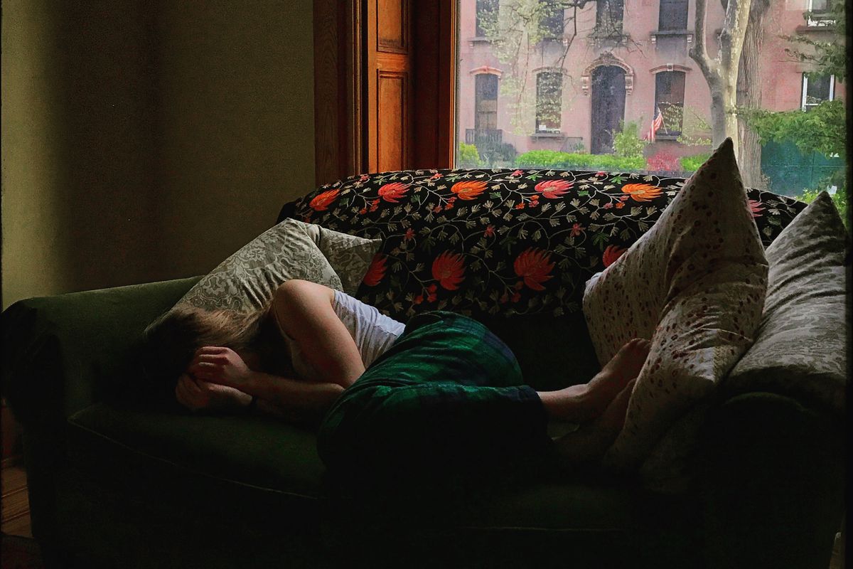 A young person curled up on a couch.