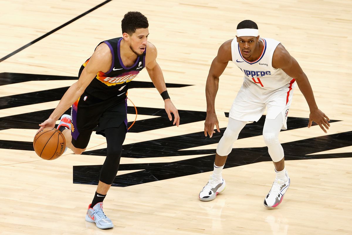 Devin Booker of the Phoenix Suns handles the ball against Rajon Rondo of the LA Clippers during the NBA game at Phoenix Suns Arena on April 28, 2021 in Phoenix, Arizona. The Suns defeated the Clippers 109-101.