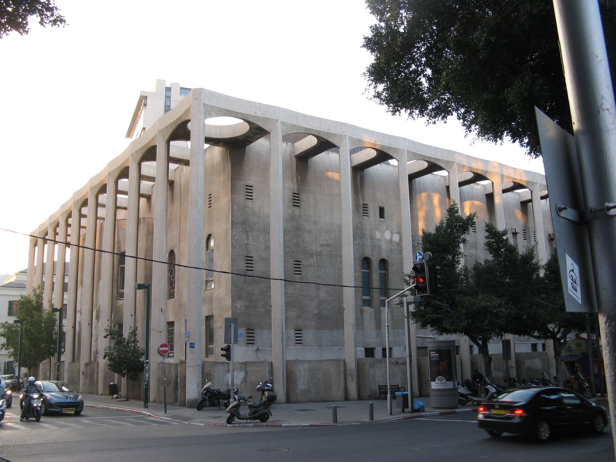 The exterior of the Great Synagogue in Tel Aviv. The facade has tall windows and a flat white roof. 