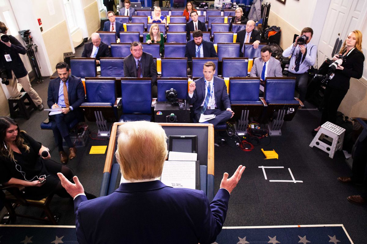 President Trump stands behind a podium while answering questions during a press briefing at the White House.