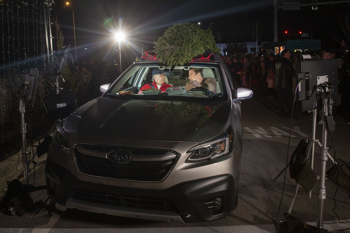 Chevy Chase and Todd Graves sit inside a modern  car with a Christmas tree on top.