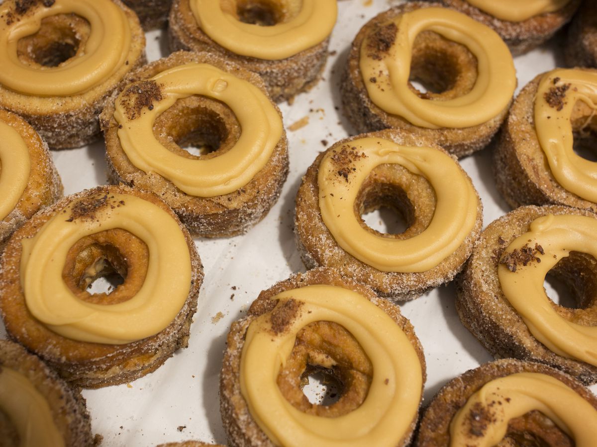 Circular fried doughnuts sit side-by-side with frosting on top.