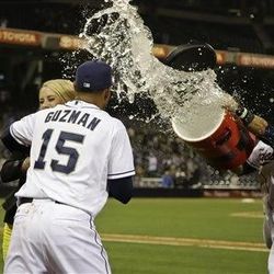 San Diego Padres' Jesus Guzman tries to hide behind a television interviewer as teammate Everth Cabrera throws a bucket of water at him following Guzman's game-winning hit in the 17th inning of the Padres' 4-3 victory over the Toronto Blue Jays in a baseball game in San Diego that started on Friday and ended Saturday.