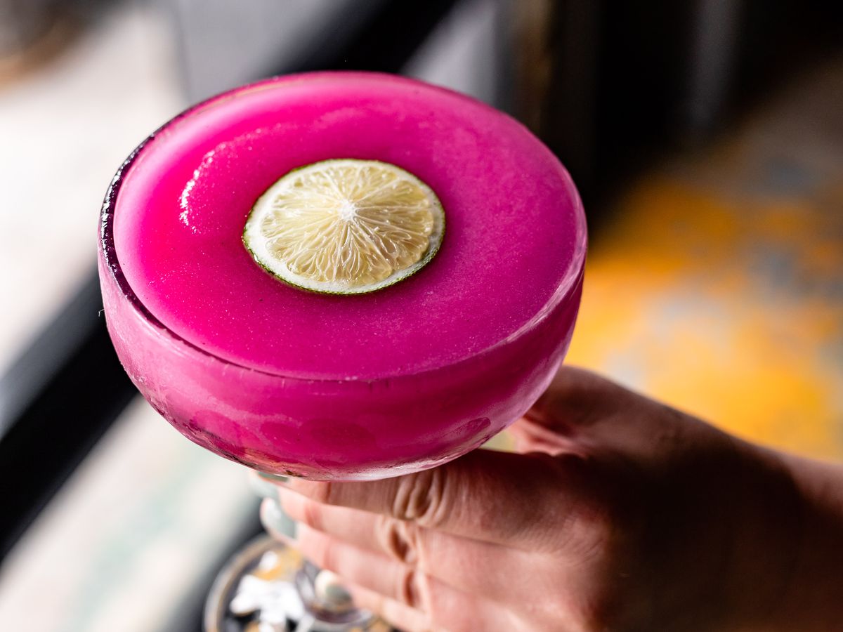 Bright pink frozen margarita garnished with lime