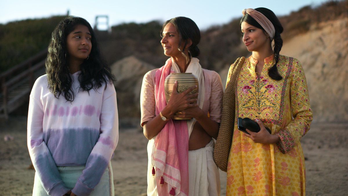 Devi, Nalini, and Kamala stand on the beach, holding Mohan’s ashes. 
