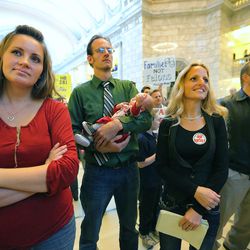 Enoch Foster, holds his son Adonijah Foster as he stands with his wives Lillian Swapp-Foster and Catrina Foster, as polygamy advocates voice their support of HB281 at a protest inside the Capitol rotunda Monday, March 7, 2016.
