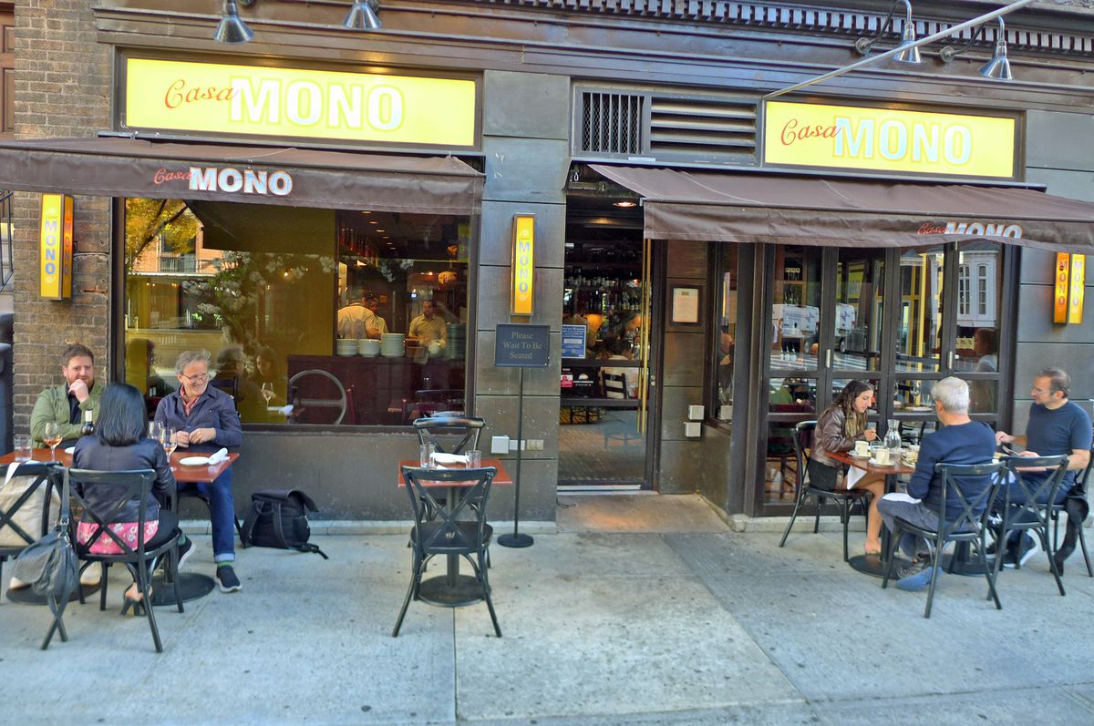A restaurant with two yellow signs above and a few people sitting at tables and laughing.