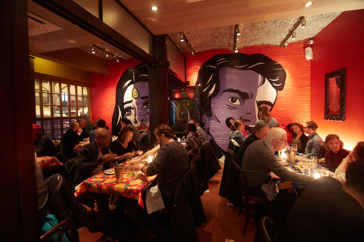 Bombay Bread Bar’s dining room, with red walls and a mural of people in the back.