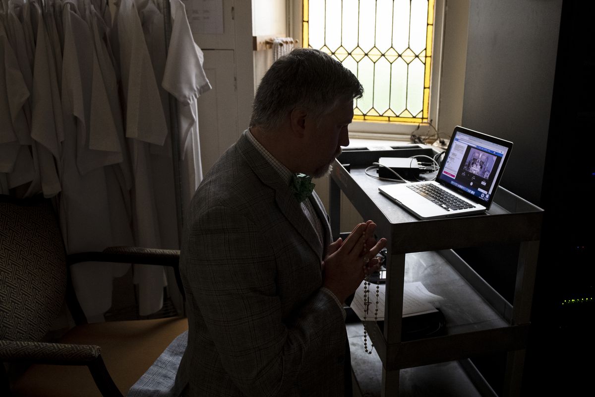Otto Beck prays as he monitors a livestream of an Easter Vigil Mass in a parlor adjacent to the sanctuary at Saint Peter’s Church on Capitol Hill without worshipers due to the coronavirus outbreak on Sunday, April 12, 2020.
