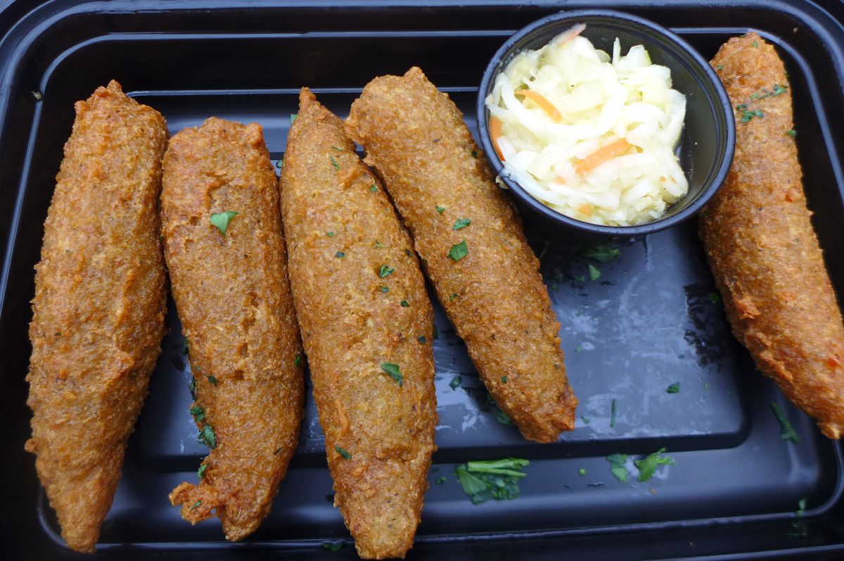 Five elongated brown fritters with a slaw in a cup on the side.