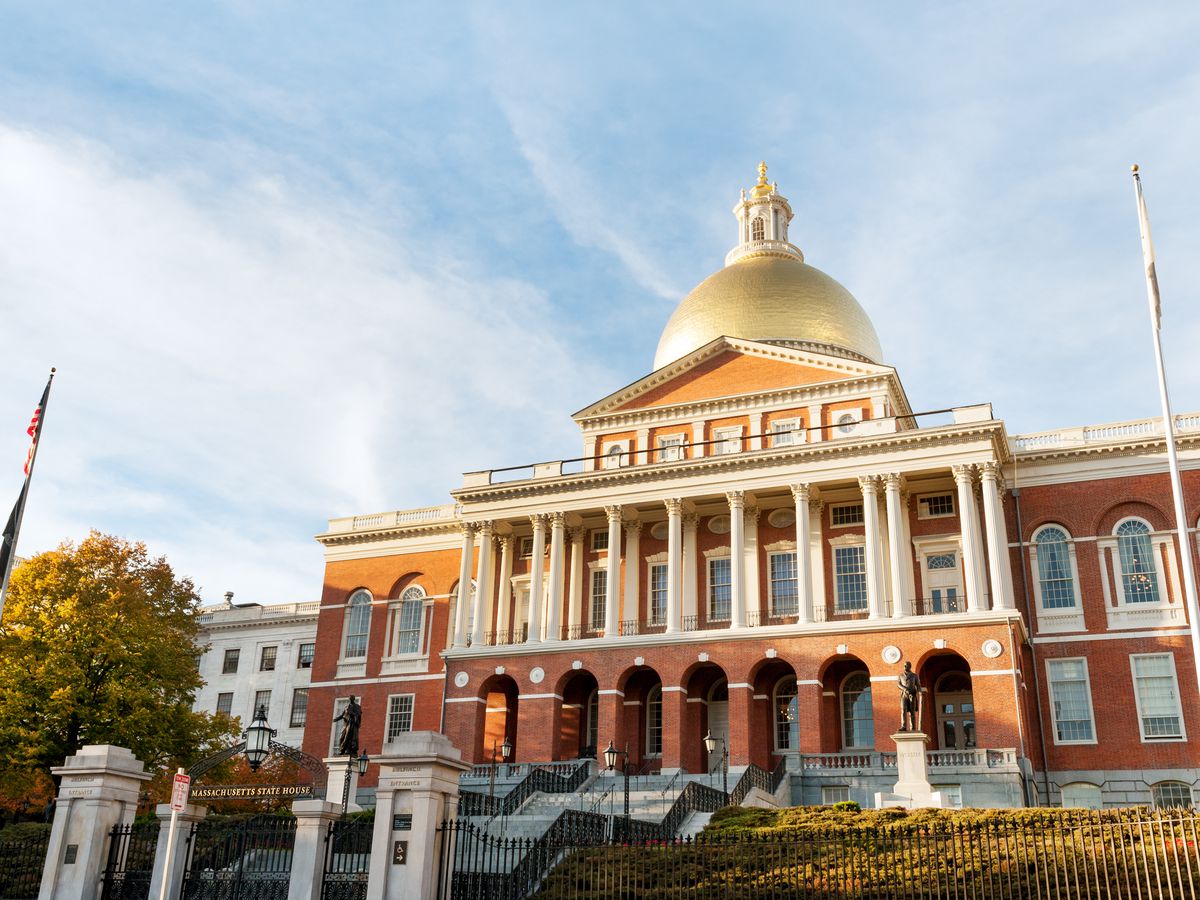 A domed building in Boston with gold covering the dome. It is the Massachusetts State House and it is just across the street from Boston Common park.