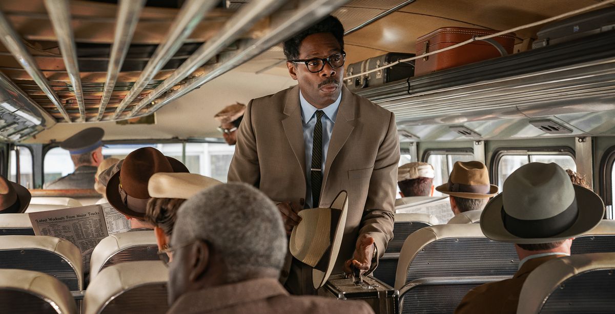 Colman Domingo, in a tan suit with hat in hand as Bayard Rustin, boards a full bus in Netflix’s movie Rustin