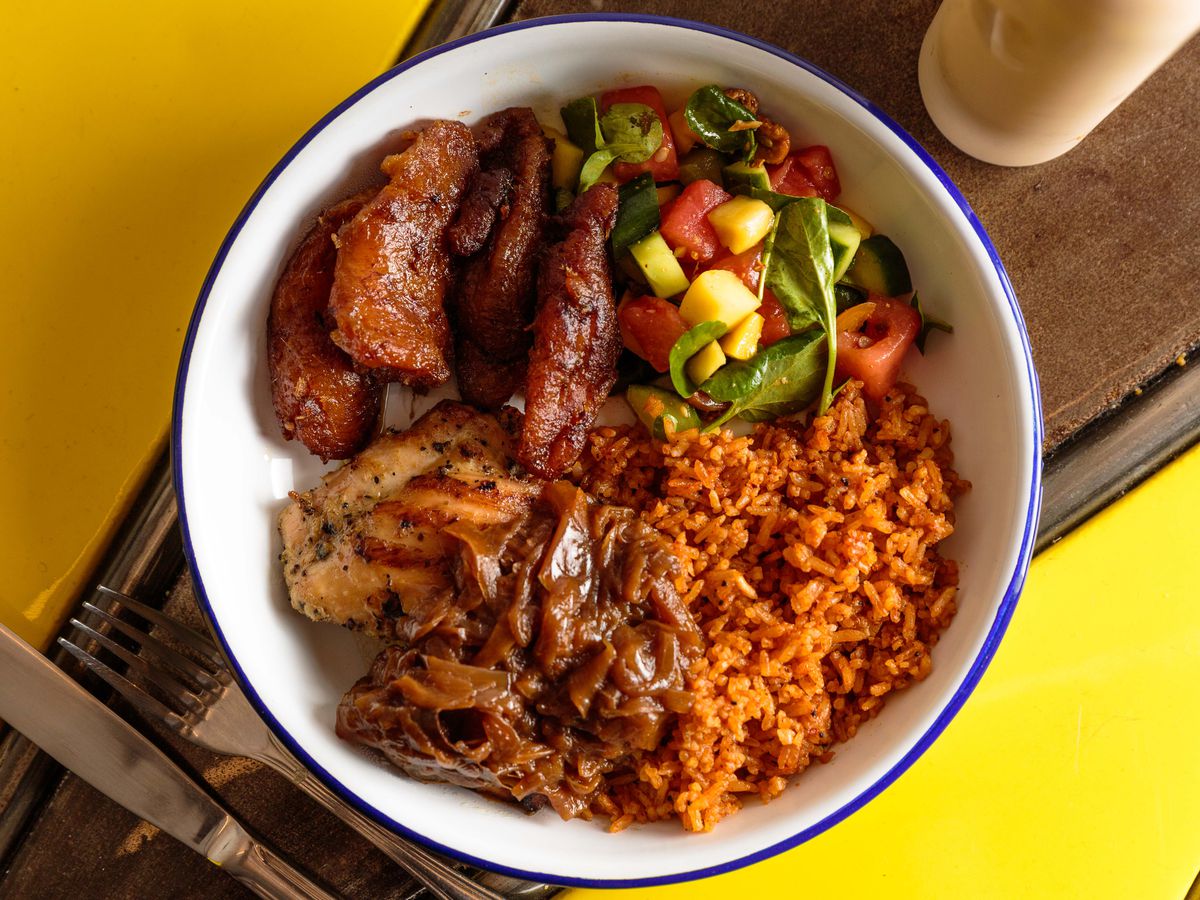Chicken yassa sits in a white bowl alongside sweet plantains and tomato rice at Teranga.