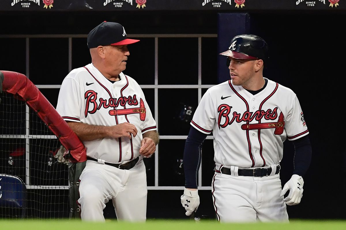 Brian Snitker of the Atlanta Braves talks with Freddie Freeman during the first inning against the Philadelphia Phillies at Truist Park on September 28, 2021 in Atlanta, Georgia.
