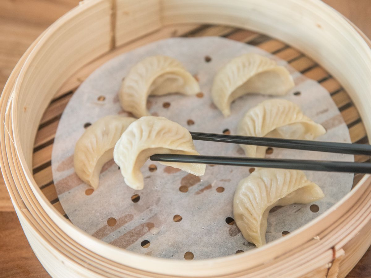 This picture shows a bamboo container with six steamed dumplings at Dough Zone.