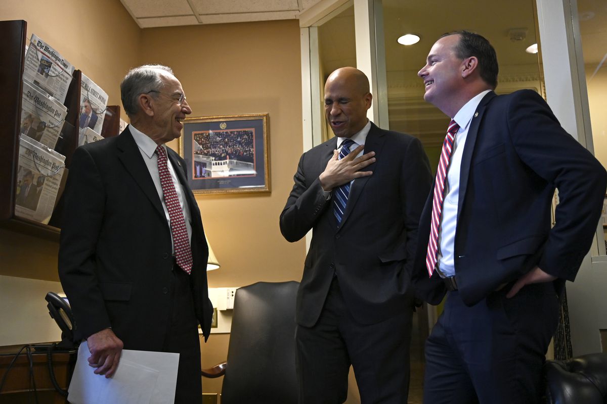 Sen. Cory Booker, D-N.J., center, talks with Sen. Chuck Grassley, R-Iowa, left, and Sen. Mike Lee, R-Utah, right, before they participate in a news conference on Capitol Hill in Washington, Wednesday, Dec. 19, 2018, on prison reform legislation. A crimina