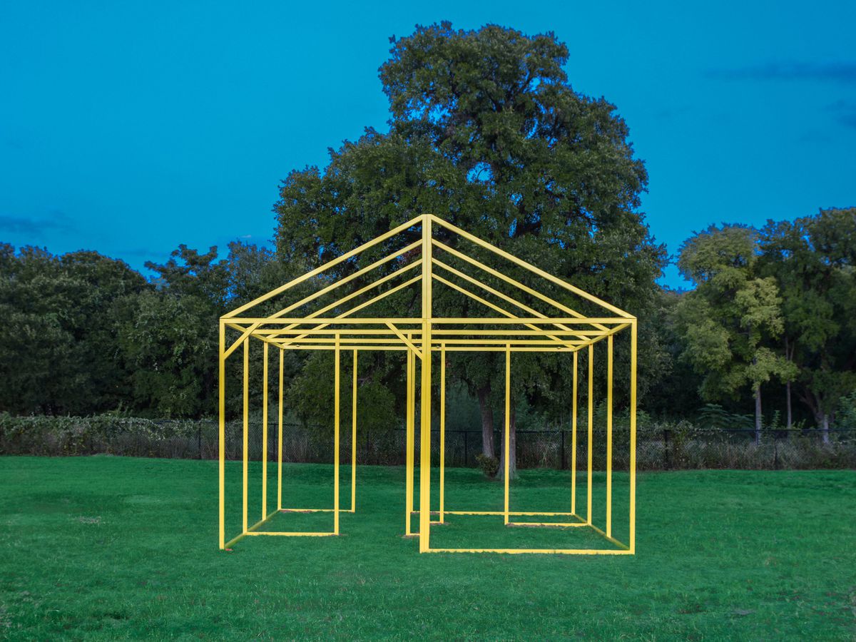 This is a work of art called Ghost House by Nick Schnitzer. It is a yellow frame of a house in a field.