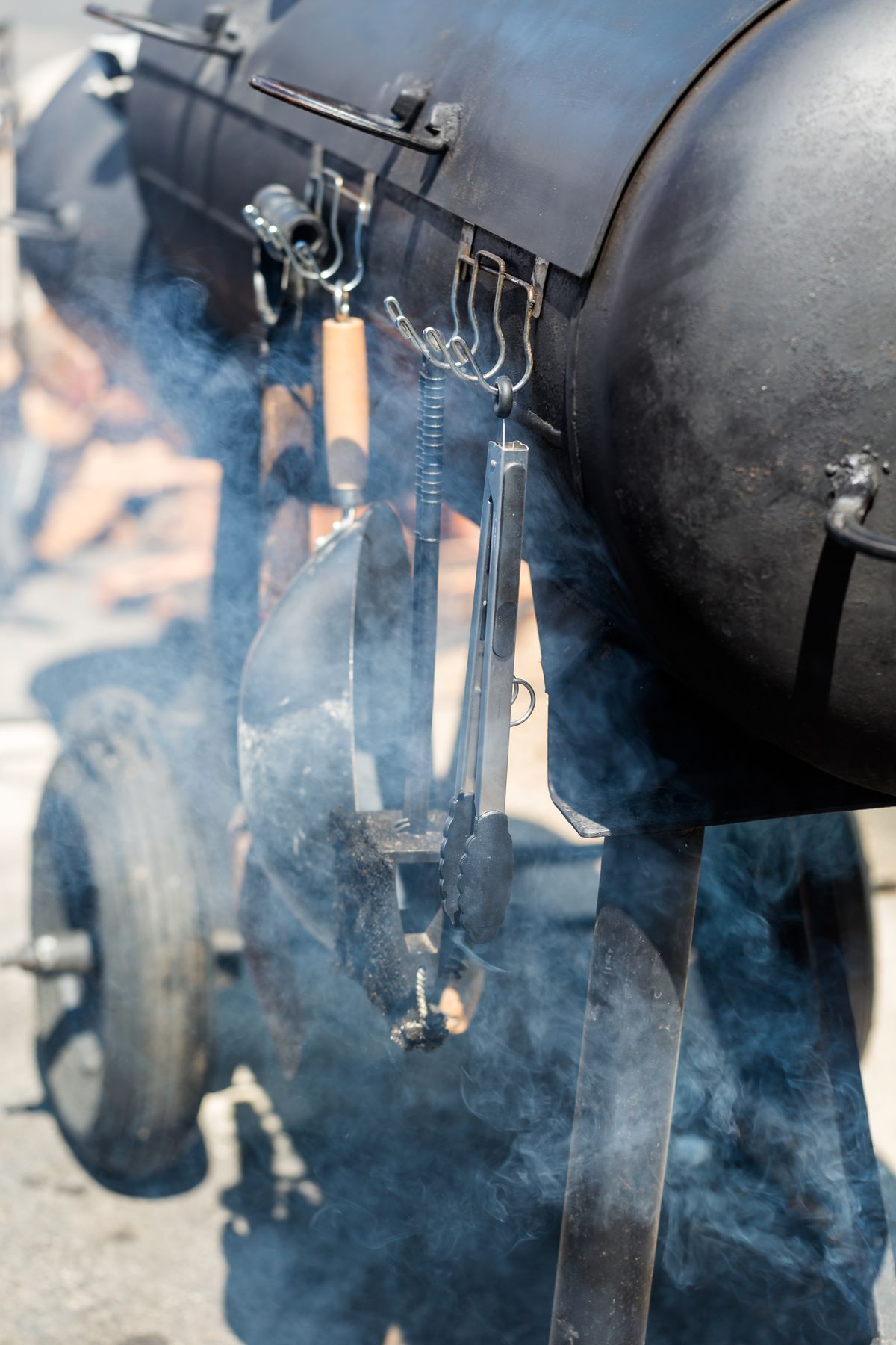 A barbecue smoker with lots of smoke coming out of it.