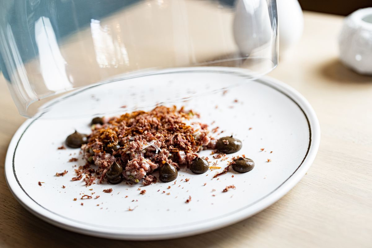 A white dish holds deconstructed beef tartare.