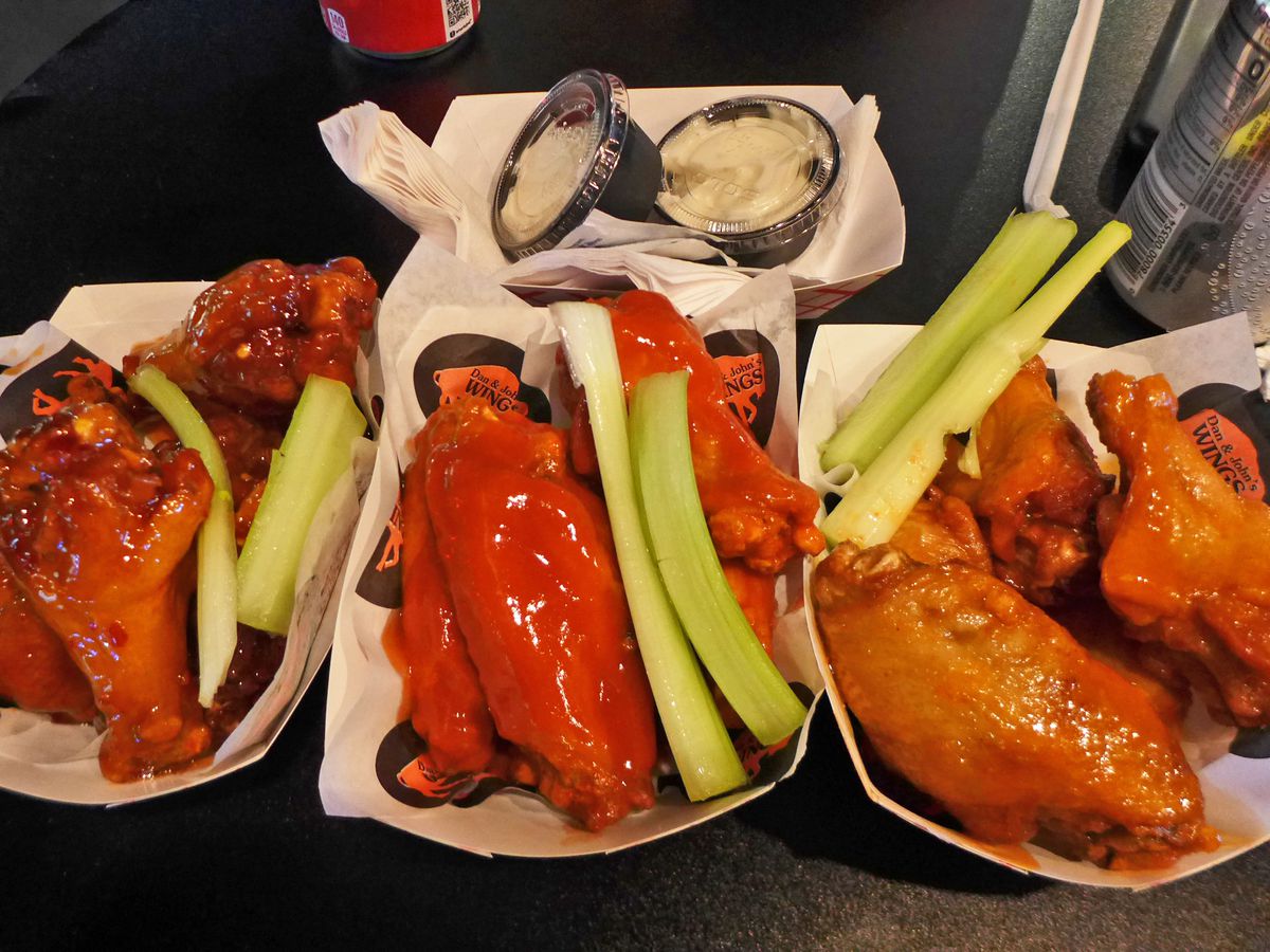Three types of wings in separate paper baskets with celery alongside.