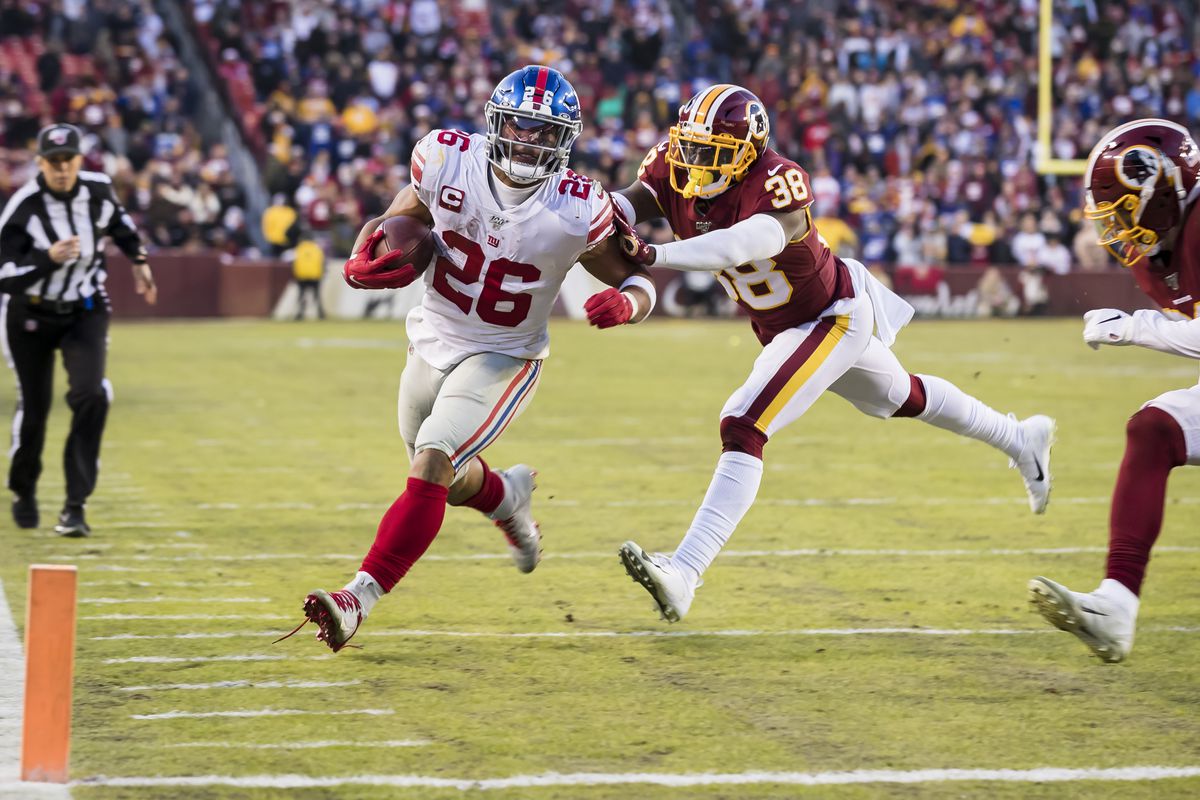 New York Giants running back Saquon Barkley gets pushed out of bounds by Kayvon Webster of the Washington Football Team