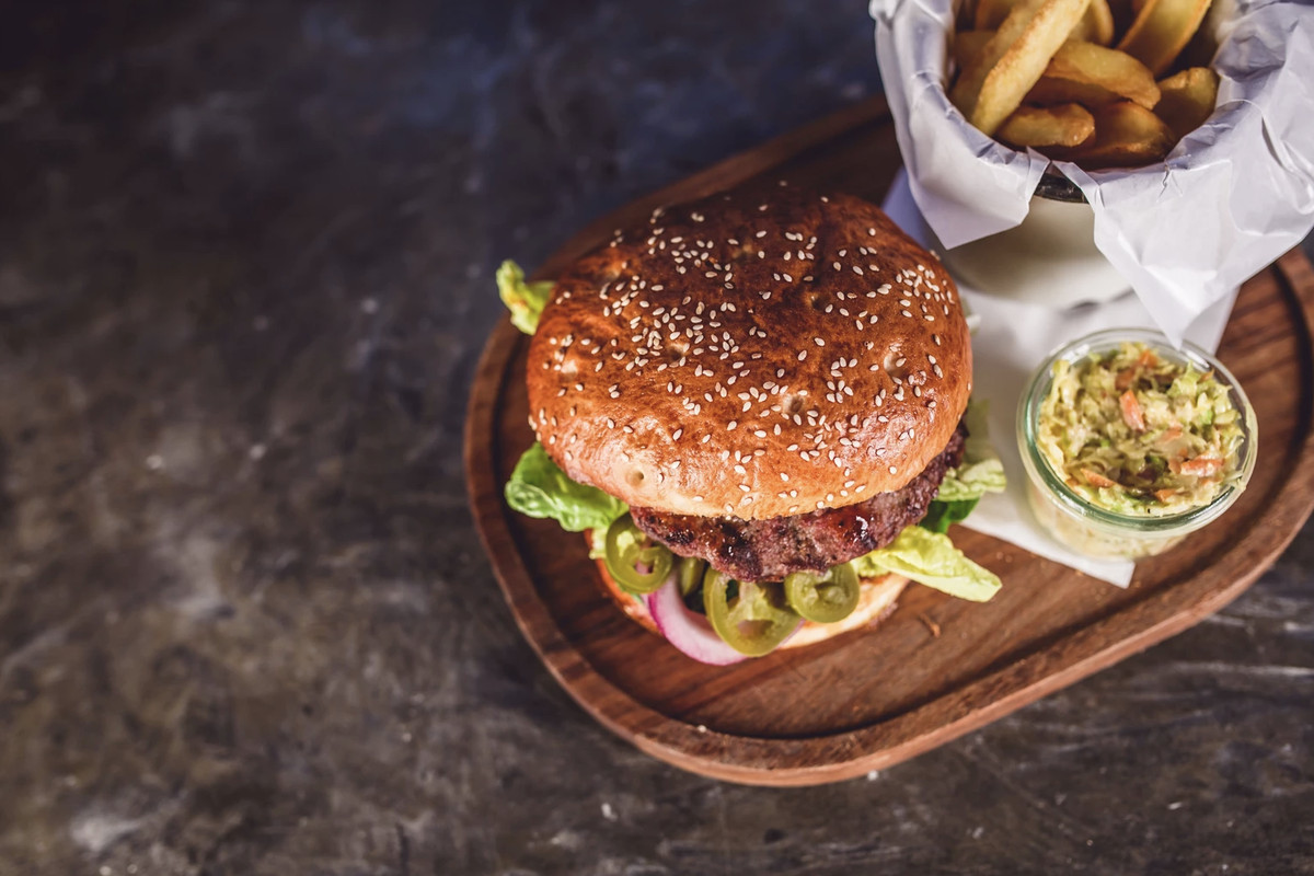 A veggie burger on a wooden plate with fries