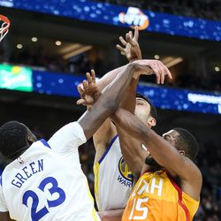 Golden State Warriors forward Draymond Green (23) and center Zaza Pachulia (27) tangle with Utah Jazz forward Derrick Favors (15) at Vivint Arena in Salt Lake City on Tuesday, Jan. 30, 2018.