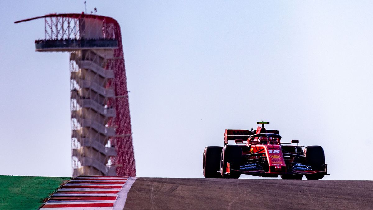 A red race car next to a tall structure in the back.