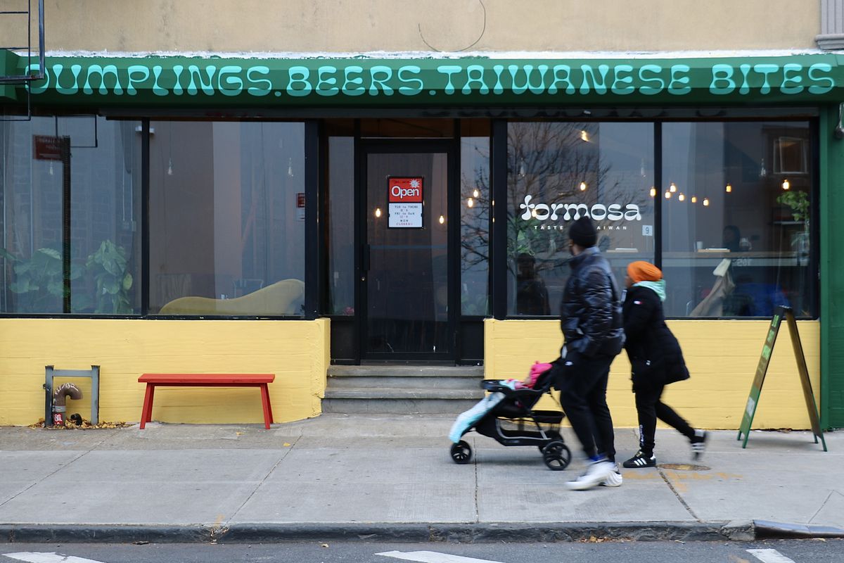 Two people walk in front of a restaurant in Brooklyn, Formosa.