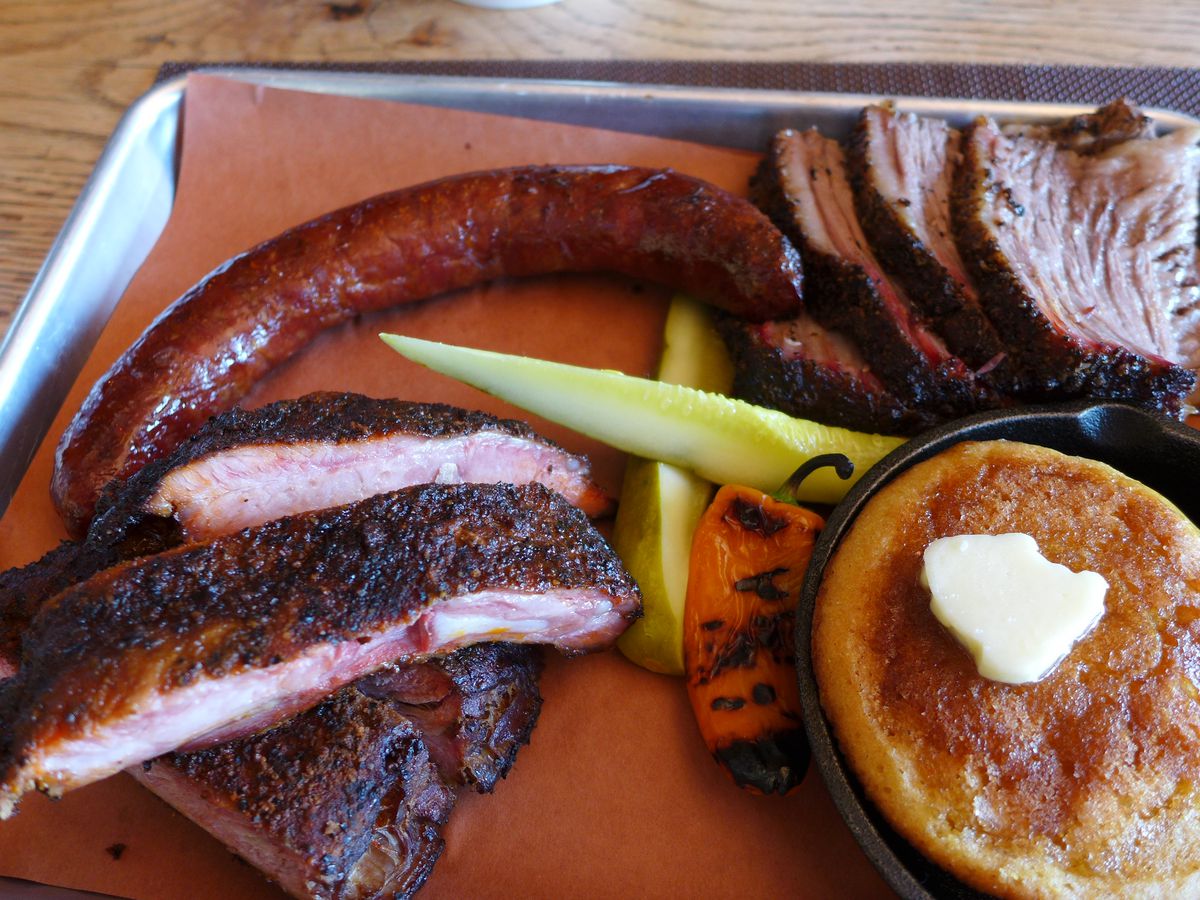A paper-lined tray with sausage, brisket, and detached ribs.