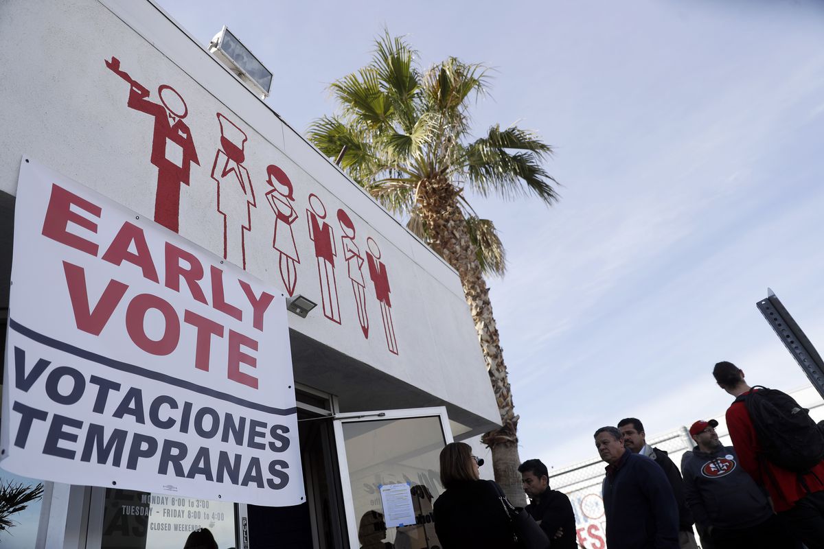 Voters line up outside a building that sports a banner reading “Early Vote / Votaciones Tempranas.”