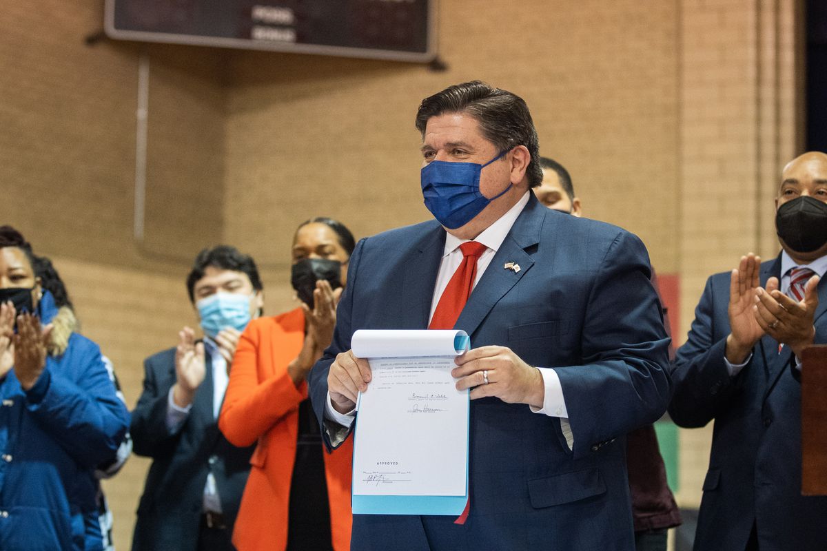 Gov. J.B. Pritzker holds a bill that he just signed during a press conference at the Washington Park Fieldhouse in the Washington Park neighborhood, Friday afternoon, Dec. 10, 2021. 