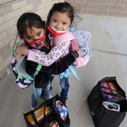 Meadowlark Elementary students Sheenay Wahmoo and Sophy Gomez hug after getting their food bags at the school in Salt Lake City on Thursday, Dec. 16, 2021. USANA’s management team delivered 385 two-week food bags for elementary students who will be out of school for the holiday break.