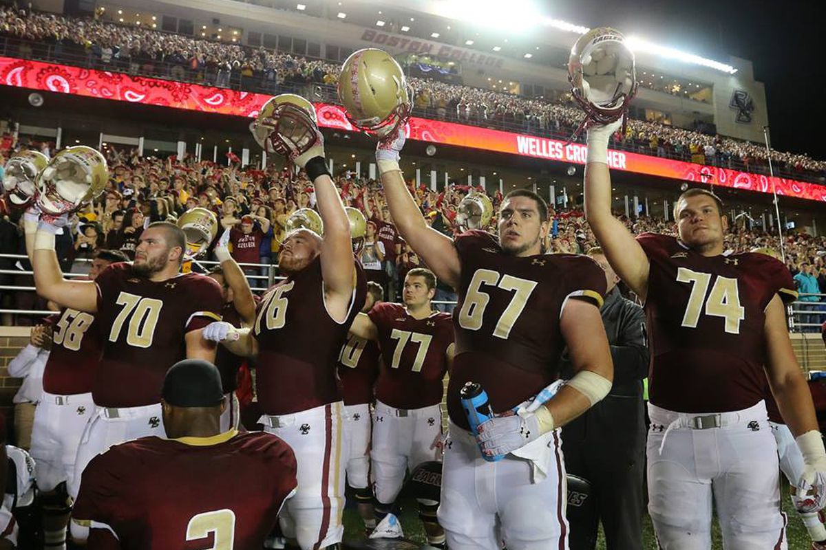 Boston College football players raise their helmets in celebration with the BC Marching Band, probably while thinking about how not cool the Band is.