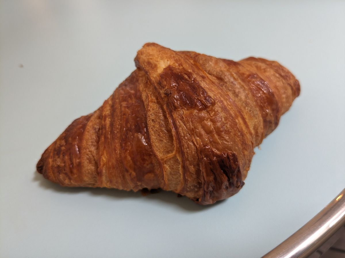 A very brown croissant turned at a rakish angle.