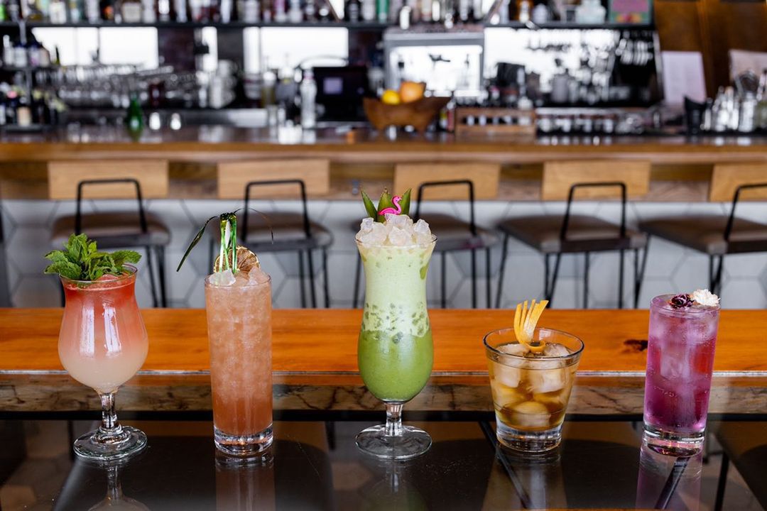 Colorful cocktails lined up on a bar.