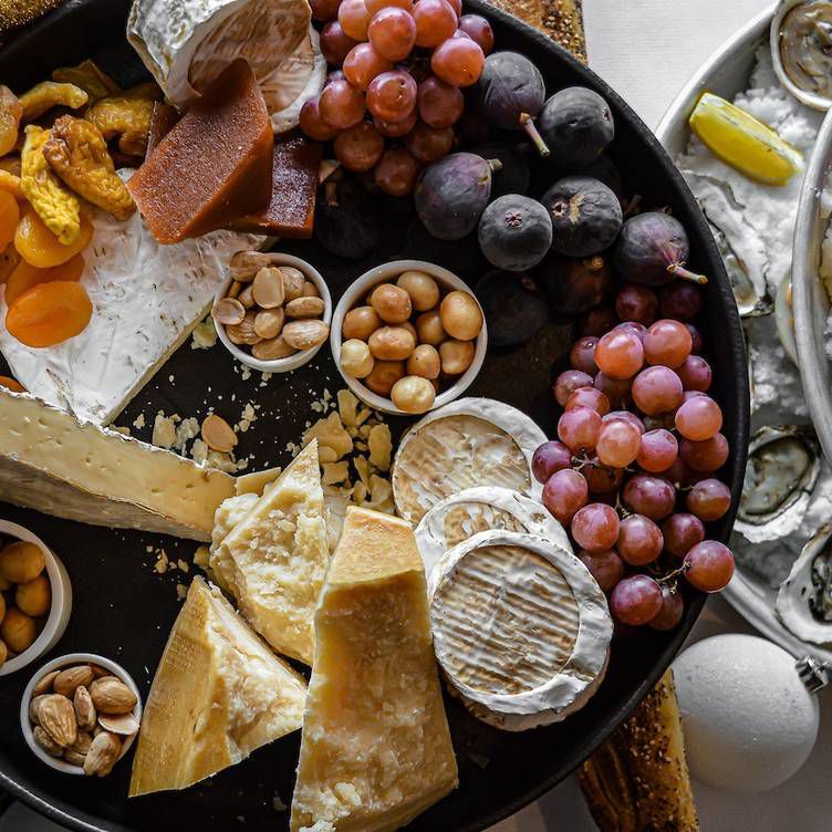 A close-up photo of an appetizing spread with crackers, brie cheese, and red grapes.