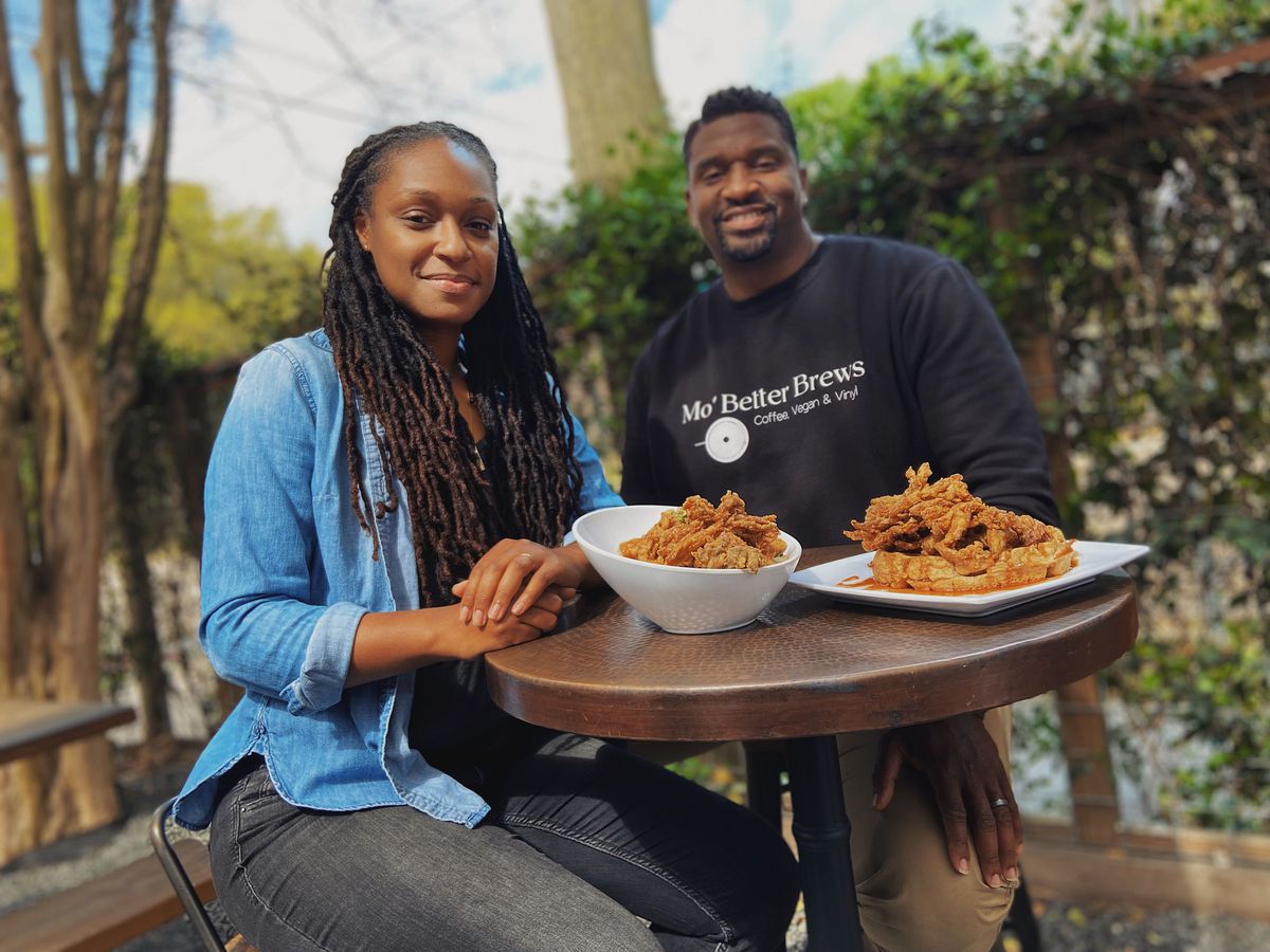 Mo’ Better Brews owners Chasitie and Courtney Lindsay sit at a table with chik’n fried shrooms and grits and chik’n and waffles.