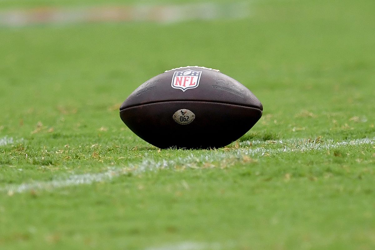 A close up view of an official leather Wilson NFL game ball with NFL logo on a natural turf grass field during the Houston Texans versus Baltimore Ravens NFL game at M&amp;T Bank Stadium on September 10, 2023 in Baltimore, MD.  