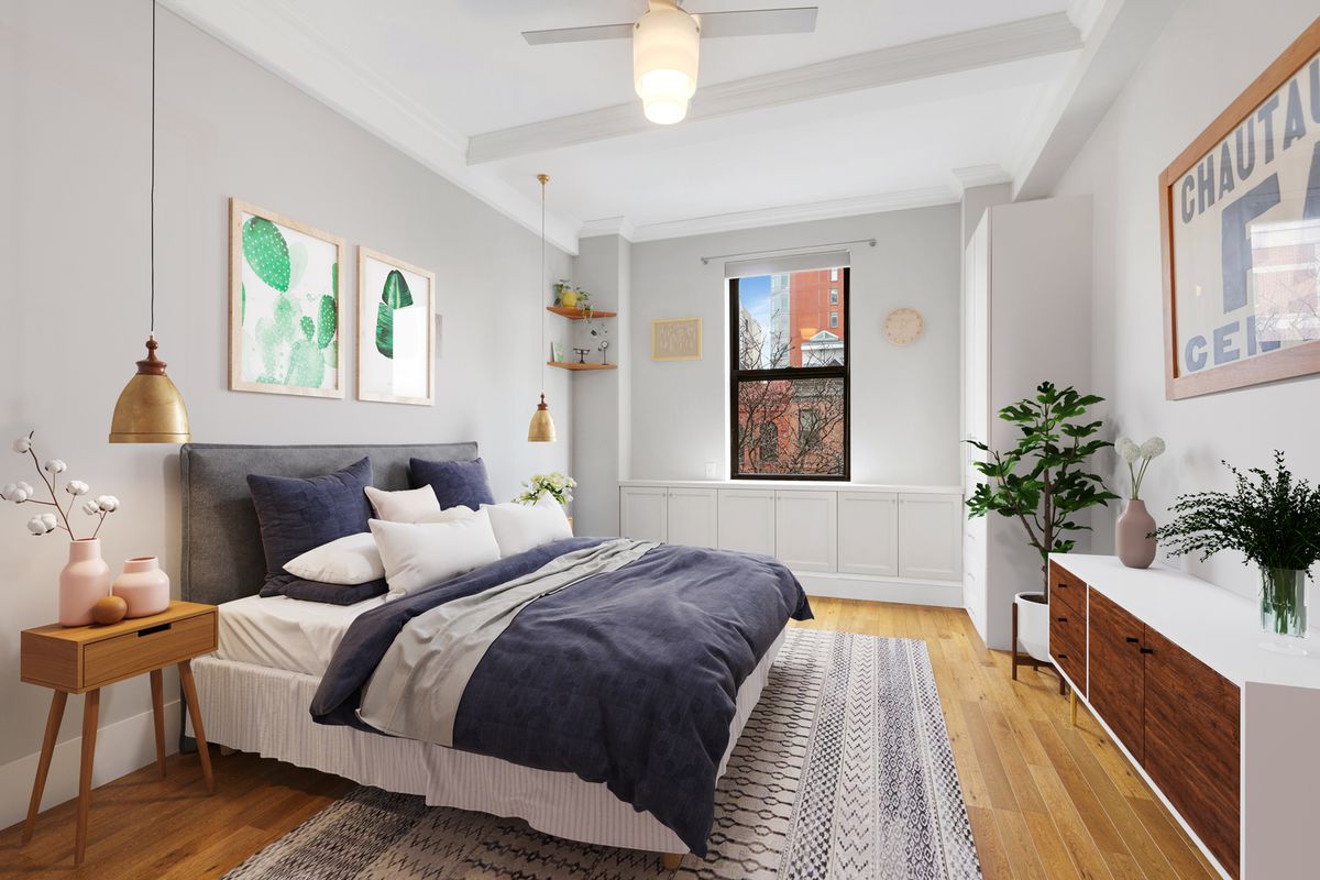 A bedroom with a large bed, hardwood floors, a planter, and a small window.