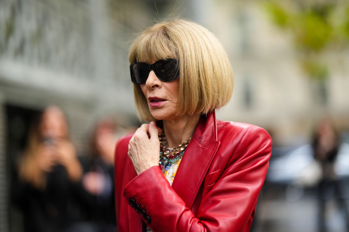 A woman wearing a red coat, Anna Wintour, is photographed in the streets of Paris.