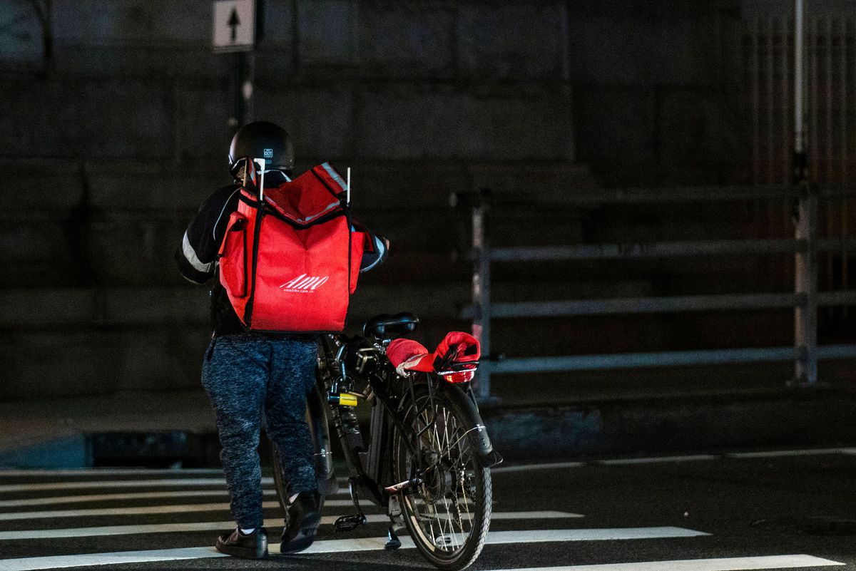 A delivery worker pushes his bicycle in Manhattan.