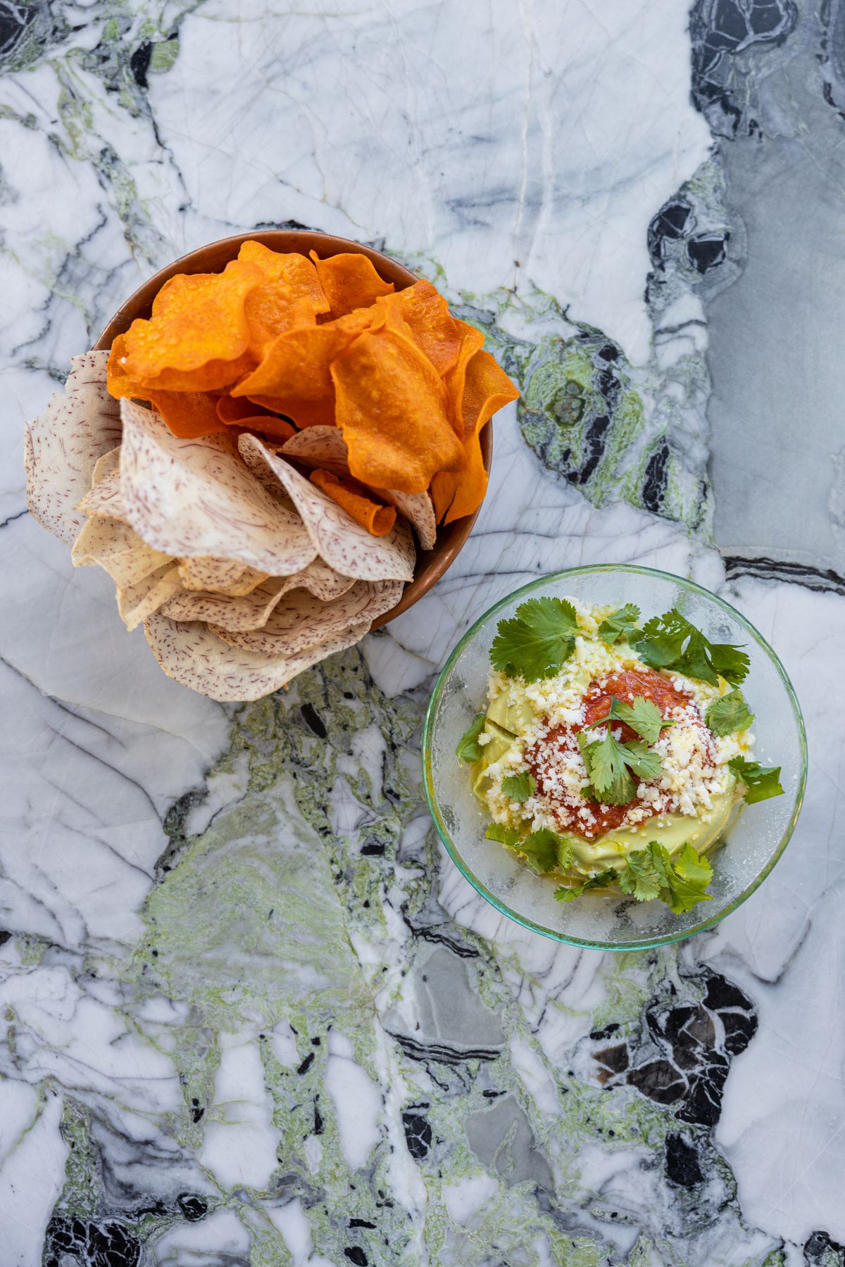 An overhead shot of vegetable chips and guacamole.