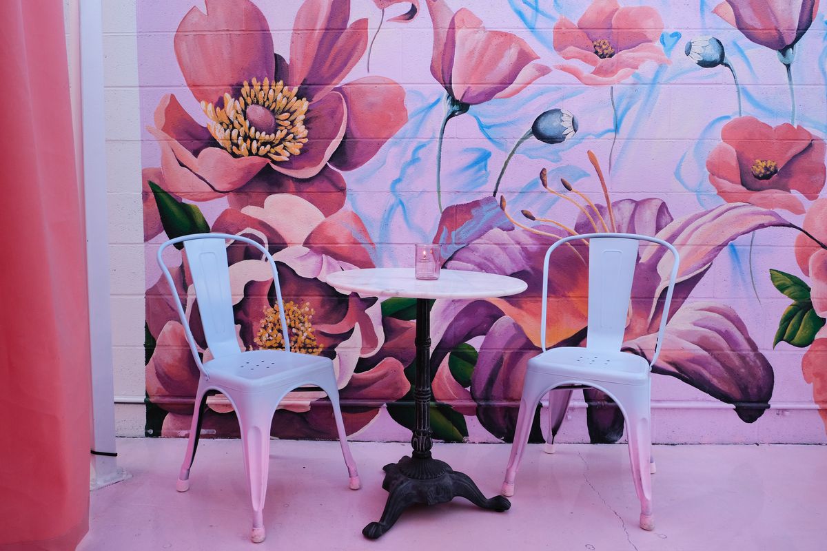 A floral mural with a table and two chairs in front of it