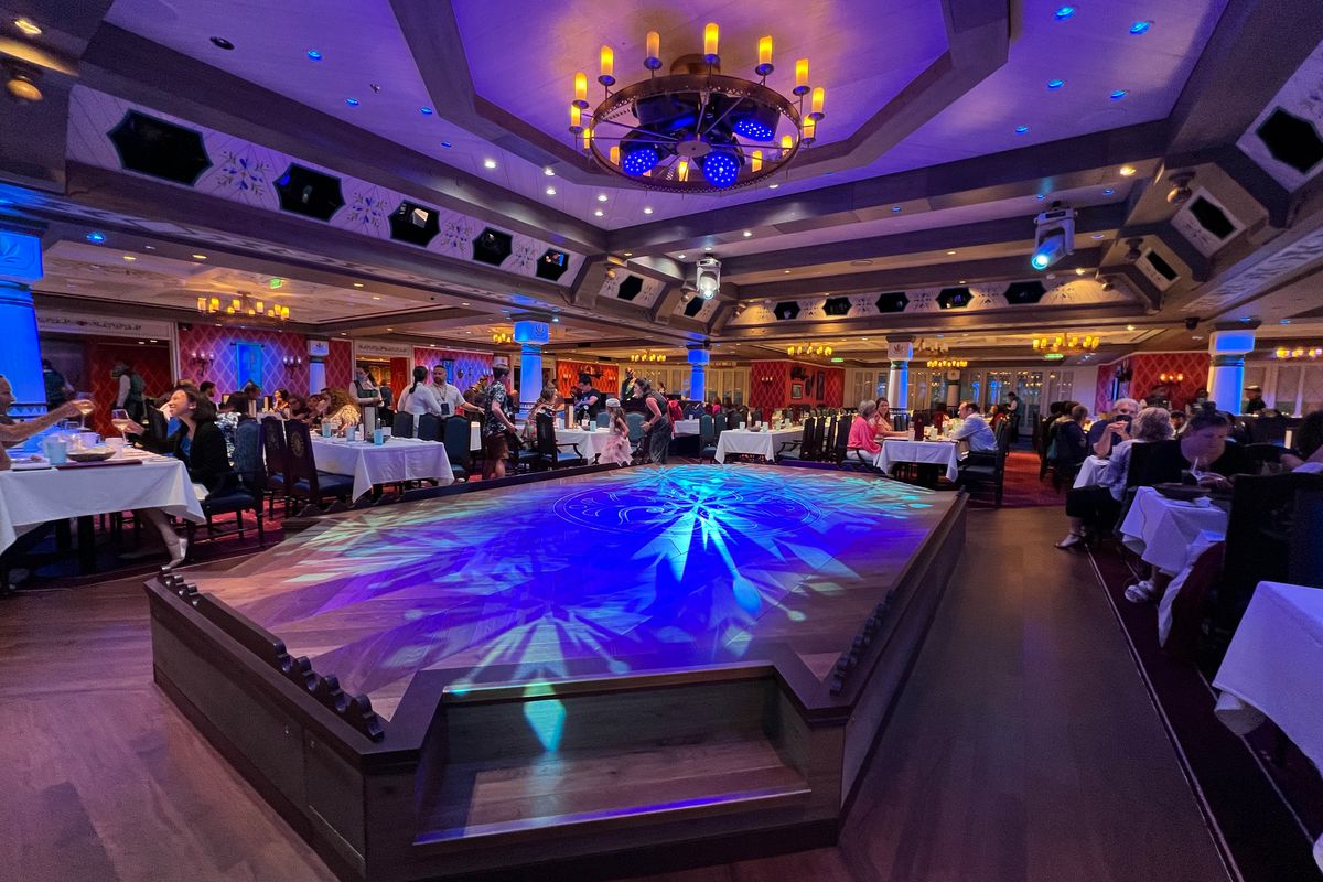 Full ballroom turned into a dining room bathed in blue light with snowflake patterns on the floor.