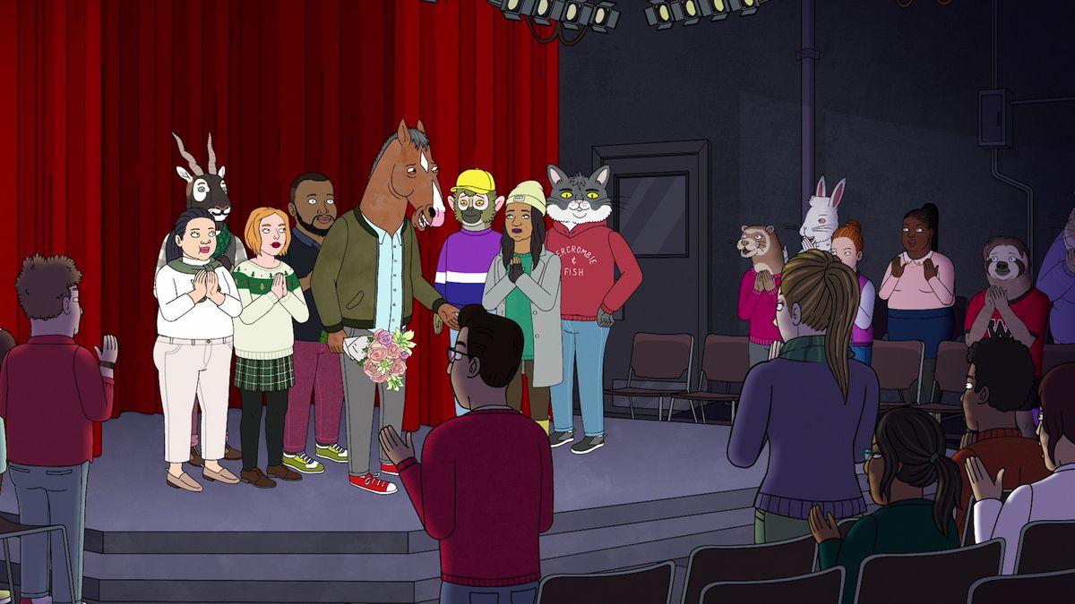 BoJack Horseman stands on a stage, holding a bouquet and surrounded by people applauding him.