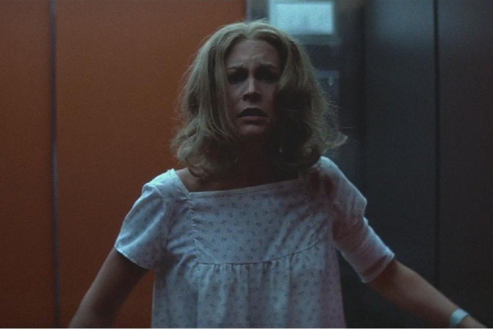 Jamie Lee Curtis looks scared while wearing a hospital gown in Halloween II.